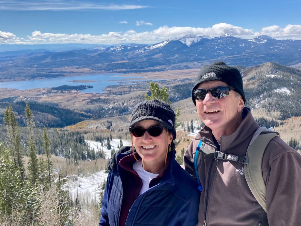 photo of Rachel and Al overlooking a vista of a distant lake and craggy mountains.