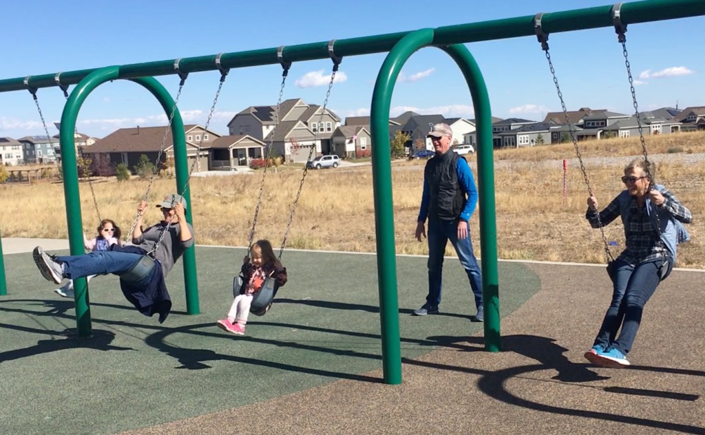 photo of adults and young children on a swingset