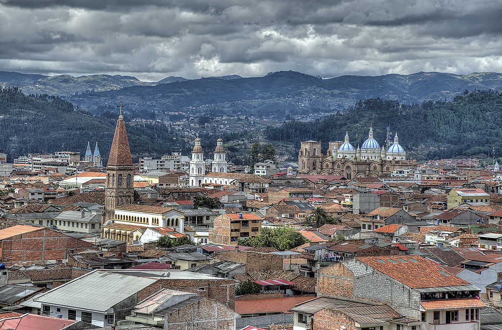 aerial photo of Cuenca, looking across red rooftops and cathedral spires toward the distant mountains