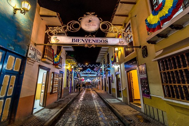 photo of a cobblestone street with storefronts and a sign reading Bienvenidos