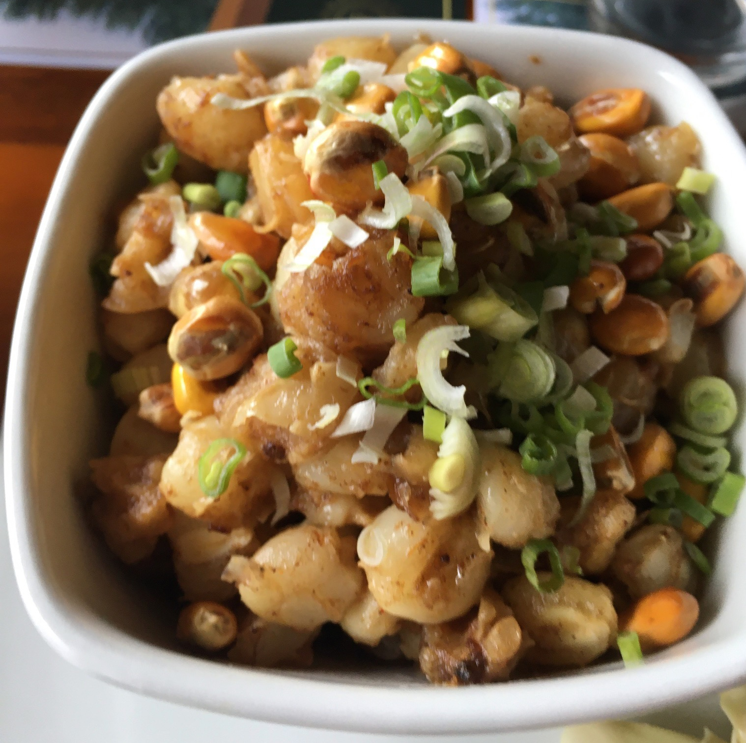 photo of a white dish containing a mixture of potatoes, corn, and scallions