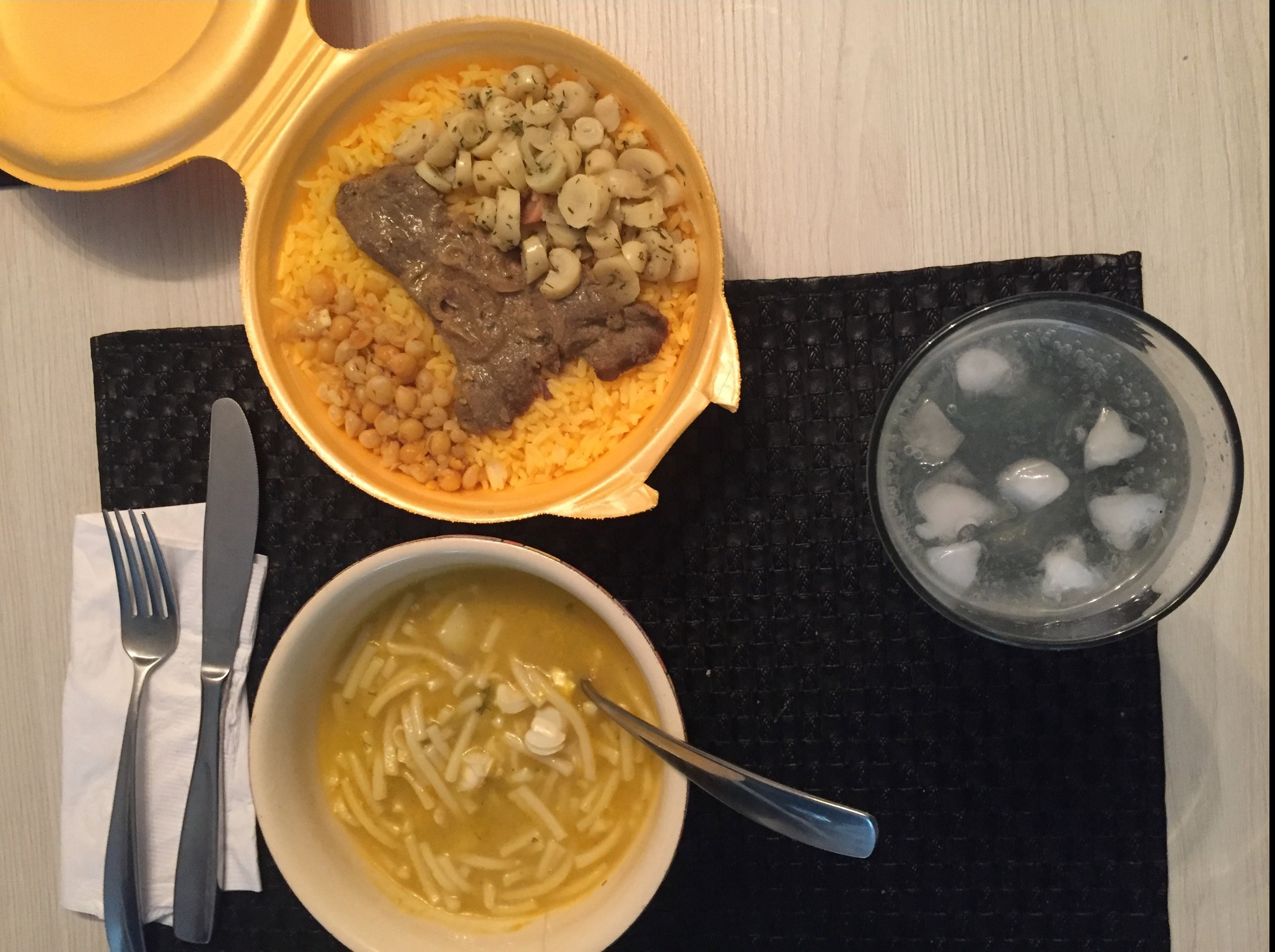 photo of a bowl of noodle soup, a plate with rice, corn, and meat, and glass of juice