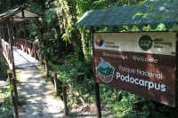 Photo of the welcome sign to Podocarpus National Park by a wooden bridge.