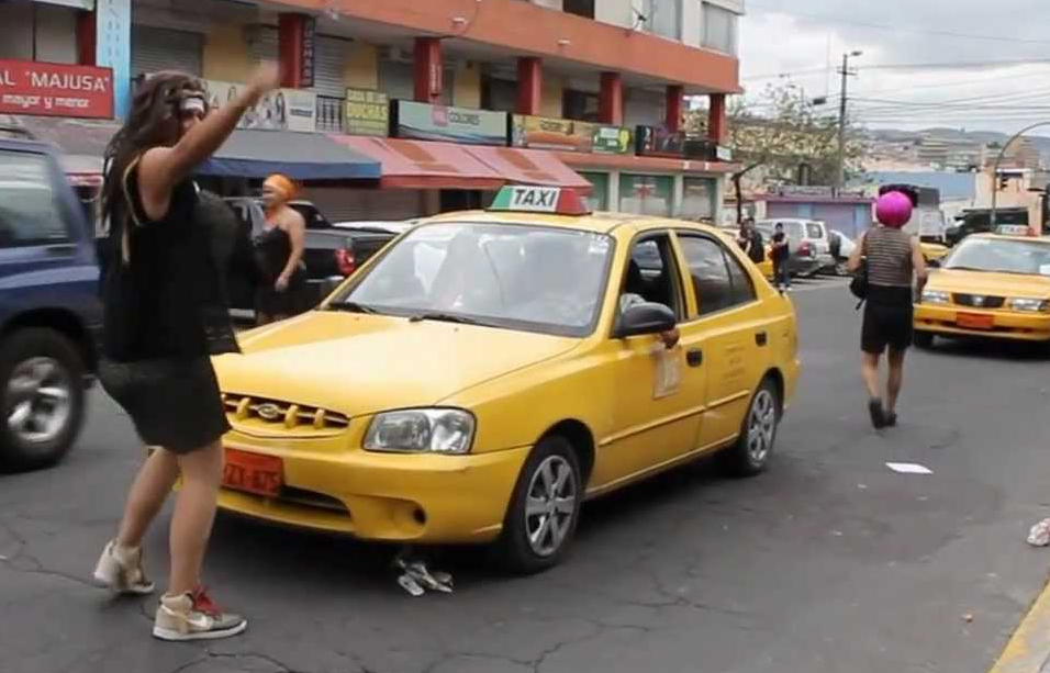 photo of a man dressed as a woman blocking the path of a taxi
