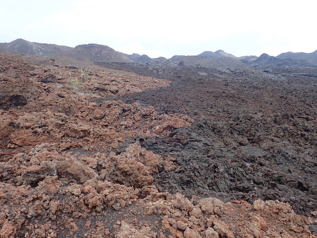 photo of dark red craggy rocks on the left, a curving border, and on the right, black craggy rocks.
