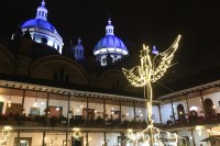 Photo of blue church domes above a courtyard with white lights in the shape of an angel.