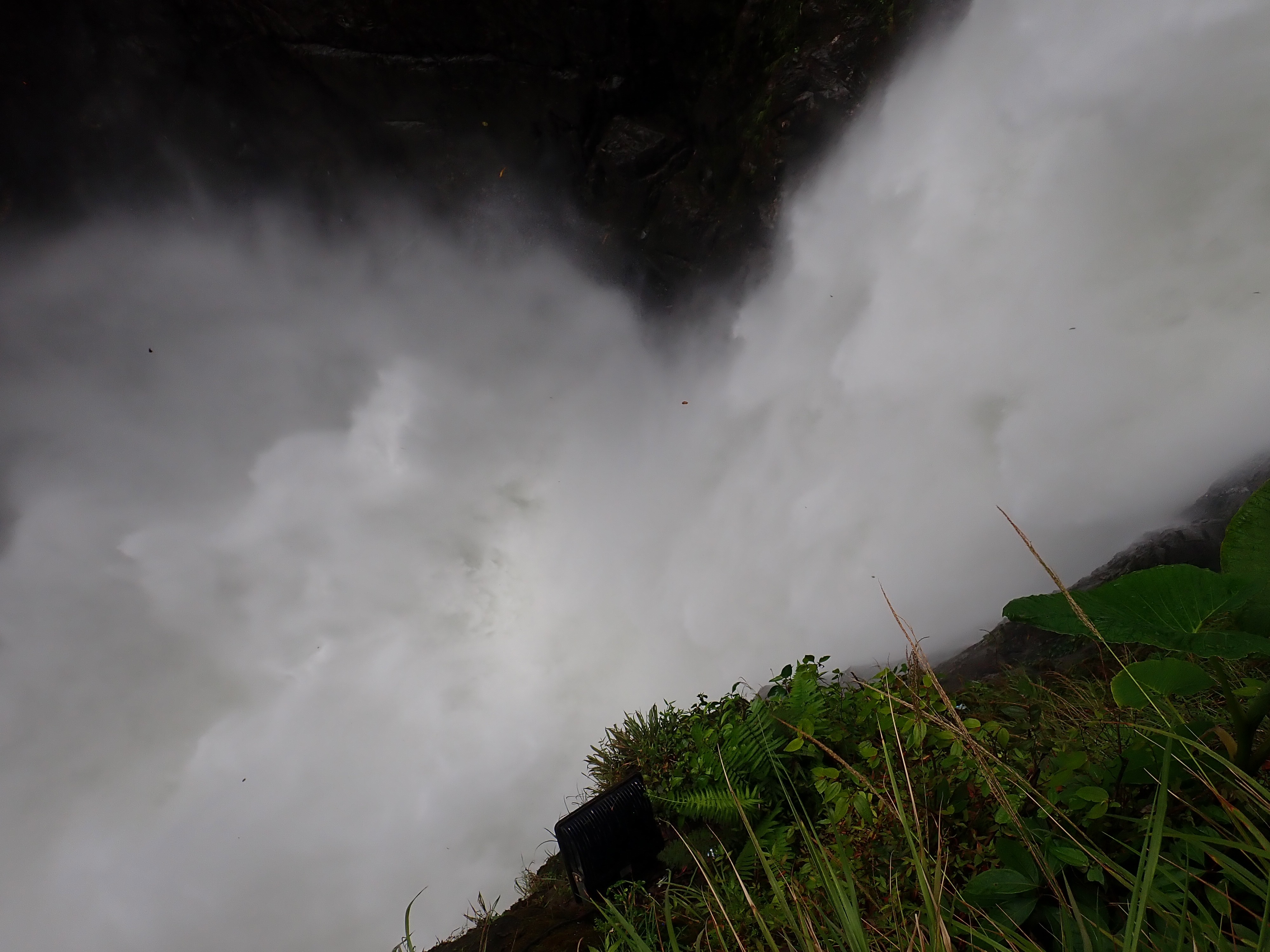 Photo of a white cascade of water plunging into a pool and spraying up.