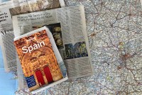 Photo of a Lonely Planet guide to Spain lying on top of two newspaper articles about Spain and a map of Spain.