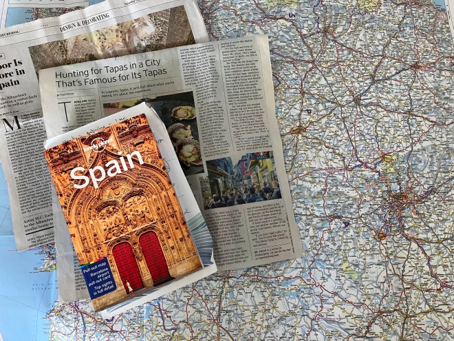 Photo of a Lonely Planet guide to Spain lying on top of two newspaper articles about Spain and a map of Spain.