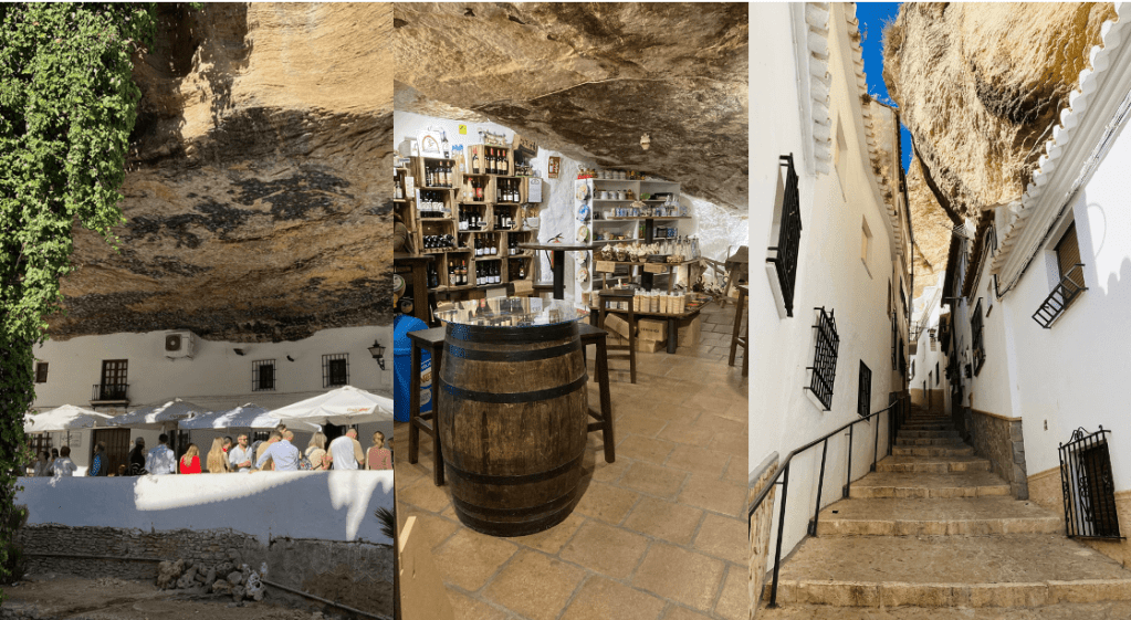 Three photos: (left): people stand under white shade umbrellas against a white, waist-high wall. Behind them is a white wall with windows, set under an overhanging rock cliff. Middle: a large wooden barrel sits on the floor of a shop with bottles on shelves behind it and an overhanging rock ceiling above Right: a narrow staircase goes uphill between two white buildings with dark-framed windows and a rock cliff overhanging.