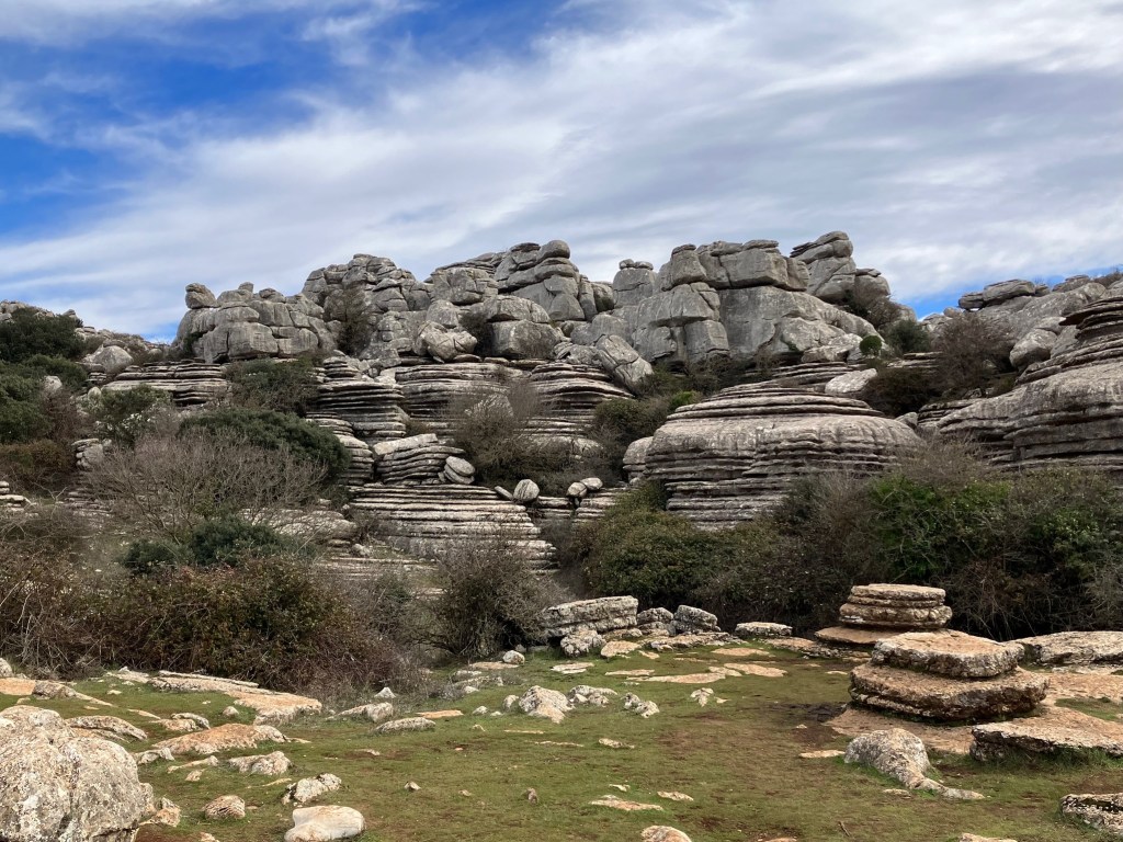 photo of grey rock formations with jumbled boulders on top of layered flat rocks like stacks of pancakes.