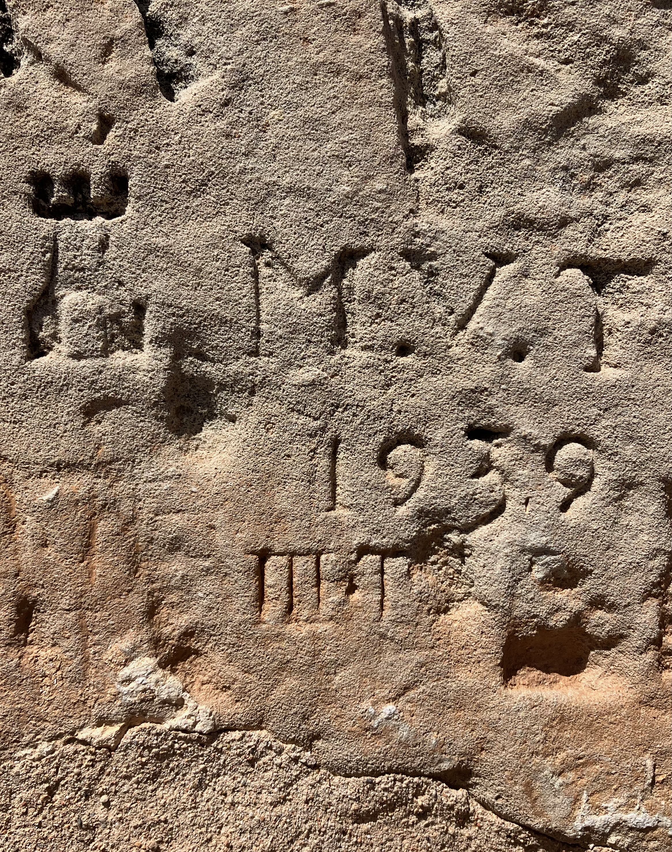 photo of a beige concrete wall with a castle turret carved into it along with the letters M.V.T. and the date 1939