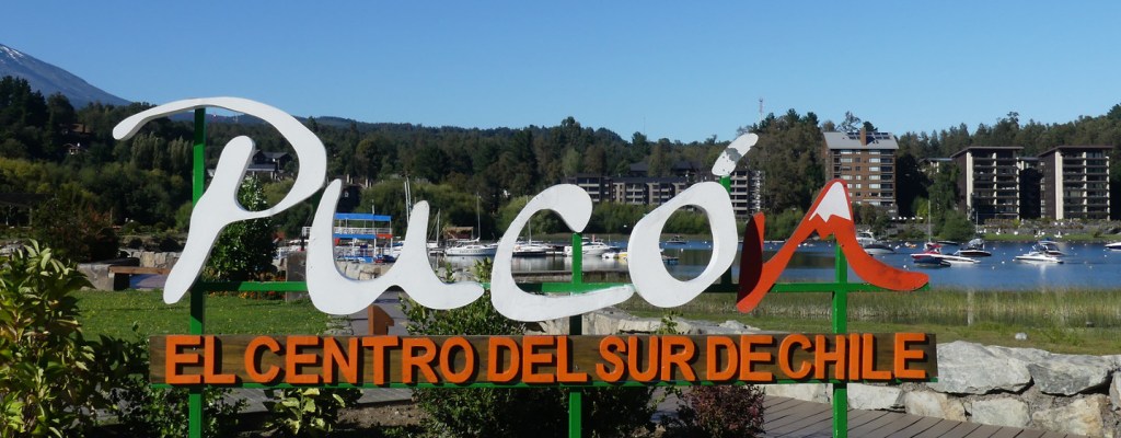 Photo of a sign with Pucón in white script (and the n shaped like a red, snow-capped volcano). Underneath in block letters the sign says "El Centro del Sur de Chile".