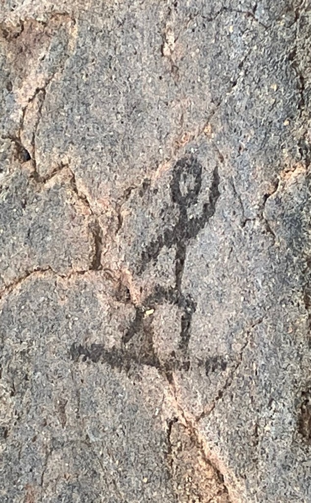 photo of a rock with lines carved into it that depict a stick-figure person on a board