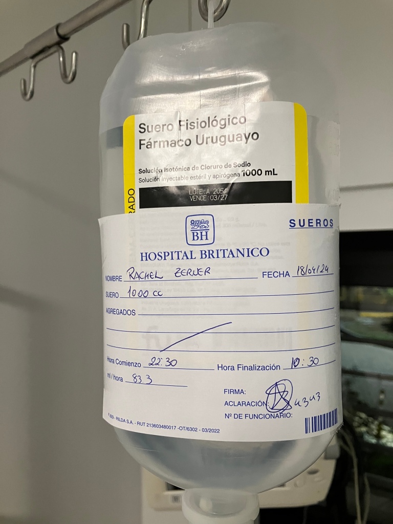 photo of a plastic saline bottle hanging from a metal hook with a label reading "Hospital Britanico"