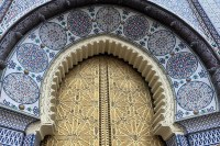 photo of an ornate, pointed-dome doorway, wth gold doors and multiple shades of blue on the archway, all embossed in complex geomtric circular designs