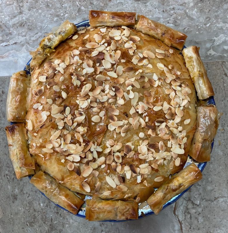 photo looking down on a round golden-brown pie with almonds sprinkled on top