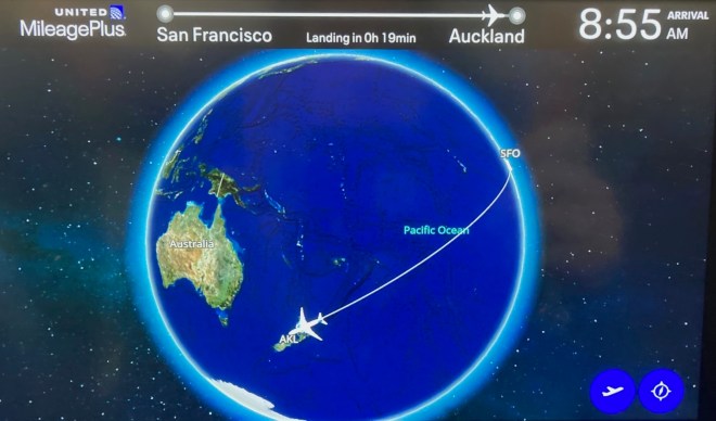 image of the globe with mostly blue Pacific Ocean and the green/yellow continent of Australia on the left, with a white line curving across the ocean and a white plane image over AKL. At the top are the words San Francisco - Auckland 8:55am Arrival.