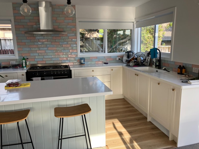 photo of a modern, spacious kitchen with white counters and a white island