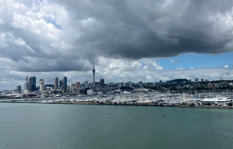 photo of a cityscape including a narrow spire and several high-rise buildings, with a large marina with hundreds of sailboats in the foreground