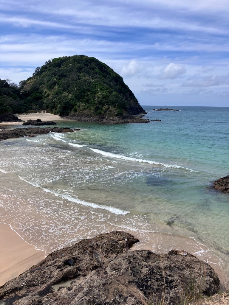 photo of light green, almost clear water washing ashore on sand and rocks