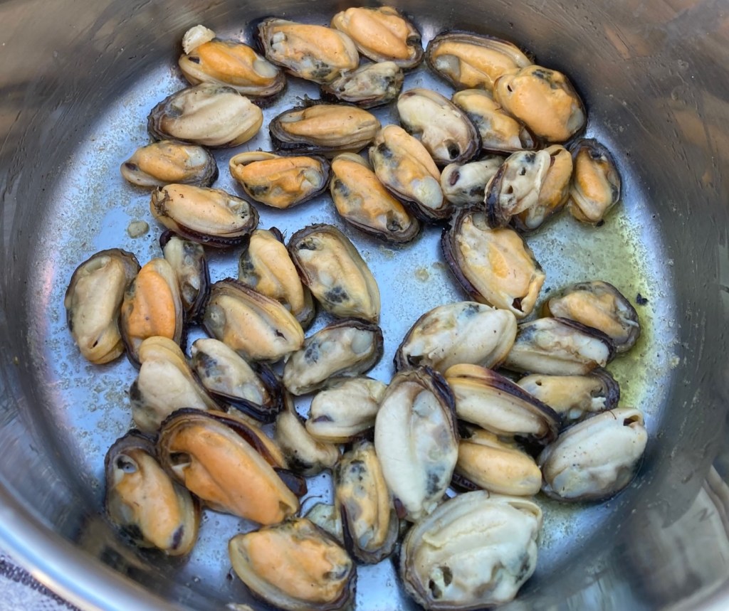 photo of orange and brown mussel meat in a silver tin dish