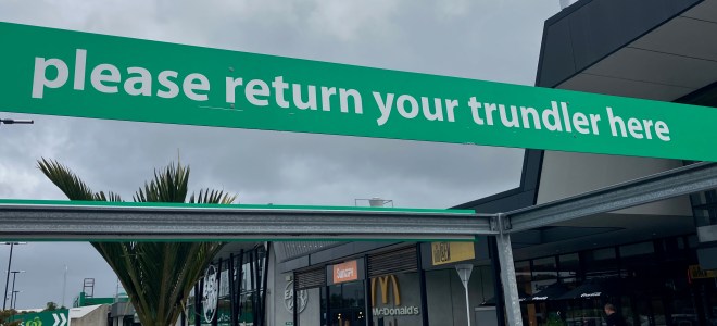 photo of a green banner with white letters saying "please return your trundler here"