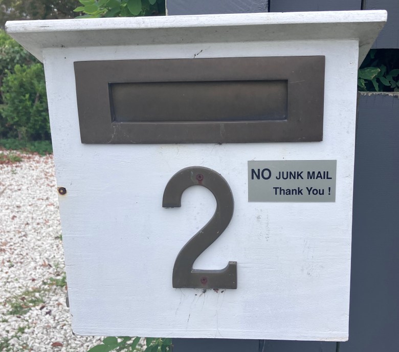 photo of a white and silver mailbox with a small sign reading NO JUNK MAIL. Thank you!