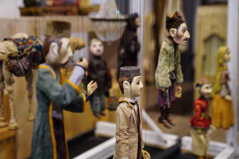photo of Japanese puppets in peasant costumes dangling from black strings