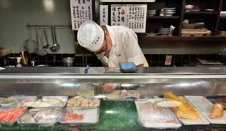 photo of a man in a white cap and jacket bending over a counter of fresh fish