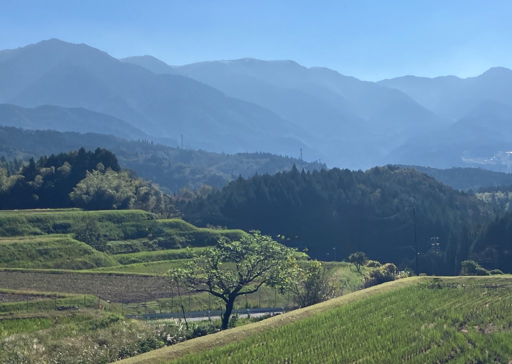 photo of layered green mountains in front of rolling hills and green fields
