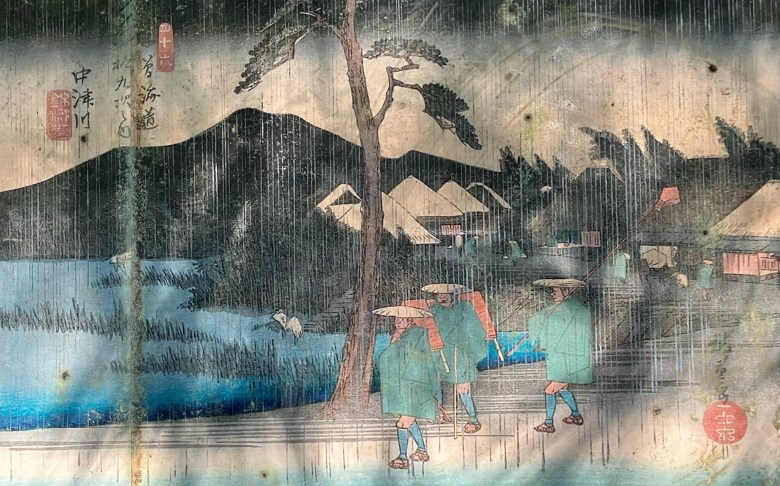 photo of an old, weathered painting of Japanese walkers on a trail with mountains in the background